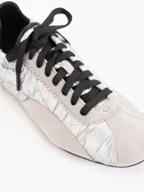 Zapatillas de estilo urbano confeccionadas en nylon plateado con detalles de cuero vacuno descarne en gris y negro. Cuentan con cordones negros y suela de goma.