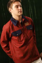 Campera roja y negra a cuadros con cuello y bolsillos de pana azul marino, cierre frontal y etiqueta con logo en el pecho.