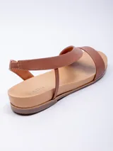 Sandalia baja de símil cuero color marrón, con doble cinta ancha cruzada sobre el empeine y tira elástica para ajuste en el tobillo.