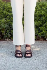 Sandalias de cuero color marrón chocolate con taco ancho, diseño de tiras cruzadas con textura símil serpiente y tira ajustable en el talón con hebilla metálica.