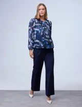 Blusa de gasa estampada con diseño circular en tonos azules, violetas y verde. Delantero plisado, puños elastizados, espalda con abertura ojal y botón.