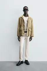 Pantalón chino de corte ajustado, color beige, con bolsillos laterales y bolsillos traseros de vivo. Cuenta con cierre frontal de cremallera y botón.