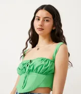 Top cropped de mujer color verde lima, estilo musculosa con escote cuadrado y tirantes. Presenta un lazo ajustable en el centro del busto y un fruncido delantero, con un recorte tipo corset en la parte inferior. La espalda es ajustada con látex.
