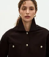Campera Marfinno de pana marrón oscuro, con cuello clásico, cierre frontal de botones metálicos dorados, bolsillos frontales con solapa y manga larga con puños abotonados.