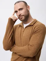 Sweater de tejido de punto en color azul, con cuello alto y cierre frontal parcial. Presenta mangas largas con puños acanalados y un pequeño detalle bordado en el pecho.