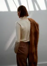 Camisa de cuello alto y manga larga, confeccionada en tejido satinado de acabado suave. Presenta un diseño recto y cierre de cremallera en la parte posterior.