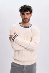 Sweater tejido de punto color crudo, con diseño trenzado y detalles de líneas azul marino en el cuello redondo y los puños.