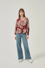 Camisa de poliéster con estampado floral en tonos bordó y crema, de corte holgado, cuello mao y cierre frontal con botones.