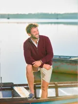 Sweater de tejido de punto fino en color azul marino, con diseño de medio cierre frontal y cuello alto. Presenta puños y ruedo acanalados, con un pequeño bordado distintivo en el pecho.