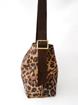 Bolso tipo hobo de tela con estampado animal print, con correa de cuero marrón ajustable con hebilla.
