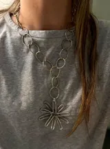 Collar plateado con cadena de eslabones circulares y dije colgante en forma de flor con pétalos de alambre.