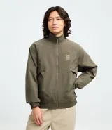 Campera rompeviento color verde militar, con cierre frontal de cremallera, cuello alto, puños y cintura elásticos. Presenta recortes delanteros y un pequeño logo estampado en el pecho.