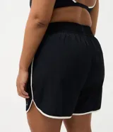 Short deportivo modelo runner de Ashua, confeccionado en poliamida con tecnología dry de secado rápido. Presenta un diseño holgado con cintura elástica, bajos redondeados con vivos laterales en contraste y detalle de lettering en el ruedo.