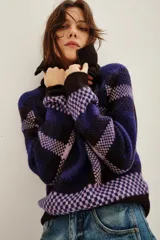 Cardigan de punto con diseño de cuadros en tonos azul, violeta y negro. Presenta cuello alto con cierre frontal y mangas largas.