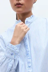 Camisa de manga larga a rayas celestes y blancas, con cuello mao y volados verticales en el frente.