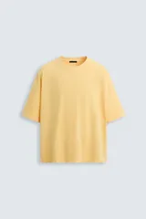 Camiseta gris de corte cuadrado y holgado, con cuello redondo y mangas cortas.