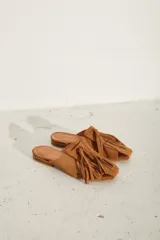 Zueco plano de cuero color dorado, con diseño destalonado, puntera cuadrada y tiras anchas entrelazadas en el empeine.