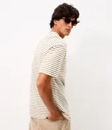 Remera boxy de hombre con diseño de rayas finas horizontales en tonos claros, cuello redondo y mangas cortas.