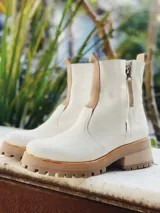 Botas de cuero color crema con cierre lateral y elástico en los laterales. Suela track color caramelo.