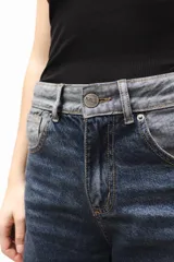 Jean de corte recto y largo, de tiro medio, color gris oscuro con efecto lavado. Presenta un bordado de estrella en los bolsillos traseros.