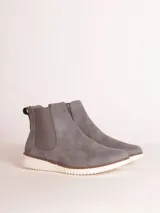 Bota tipo chelsea de estilo urbano, confeccionada en material sintético color gris con paneles elásticos laterales a tono y suela de goma blanca con relieve dentado.