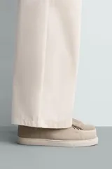 Zapatilla urbana de hombre confeccionada en piel con acabado de serraje, diseño minimalista con cordonera oculta y suela de goma a contraste.