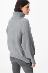 Sweater de punto con textura acanalada, cuello alto tipo polerón, mangas largas con diseño abuchonado y puños anchos.