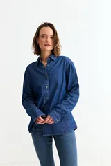 Camisa de jean de manga larga con cuello clásico y cierre frontal de botones. Presenta un diseño de corte recto y acabado en tono azul índigo.