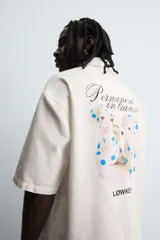 Camisa de corte relajado confeccionada en algodón, con cuello bowling y manga corta. Presenta cierre frontal con botones y detalle de texto estampado en el pecho.