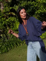 Collar con dije metálico en forma de estribo y tira de cuero color rojo. El dije es de color plateado.