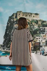 Vestido camisero corto, con cuello mao, botones a tono y parche con logo en el frente. Diseño a rayas verticales negras y blancas.