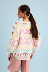 Buzo oversize de punto color marfil con diseño geométrico jacquard en tonos rosado, amarillo, celeste y marrón. Cuenta con cuello redondo y mangas largas.