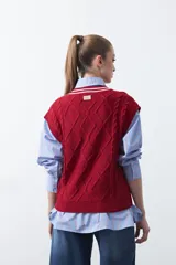 Chaleco de punto color bordó, con diseño de rombos y trenzas en relieve. Escote en V con ribete blanco y rojo.