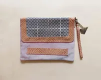 Sobre de mano Carolina De Cunto confeccionado en cuero combinado con texturas y estampados variados. Cuenta con cierre superior YKK, correa de mano corta y herrajes metálicos en tono oro viejo.