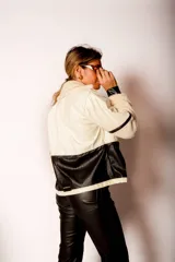 Campera corta de cuero sintético color crema y negro, con cuello, puños y ruedo de corderito.