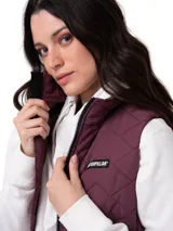 Chaleco acolchado color violeta con diseño de costuras en zigzag. Cuenta con cierre frontal central, cuello alto, bolsillos laterales con cierre y forro interno con logo estampado. Presenta tecnología resistente al viento y al agua con aislamiento térmico reciclado.
