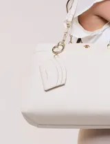 Cartera de hombro de cuero sintético beige, con estructura tripartita de compartimento central con cierre y dos compartimentos laterales con broche magnético. Posee asas dobles con detalles de cadena metálica dorada y un tarjetero independiente desmontable.