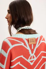 Buzo oversize de punto color marfil con diseño geométrico jacquard en tonos rosado, amarillo, celeste y marrón. Cuenta con cuello redondo y mangas largas.