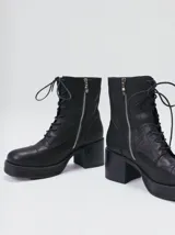 Bota de cuero tipo borceguí con cordones, cierre lateral metálico y taco cuadrado alto con plataforma. Presenta punta cuadrada y diseño robusto.