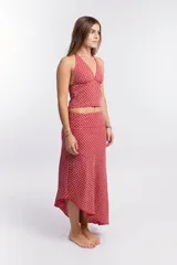 Pollera larga de tela liviana color rojo/rosado con estampado geométrico en blanco. Diseño asimétrico con corte irregular en el ruedo.