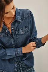 Camisa de estilo tejano en color negro lavado, con cuello camisero, cierre frontal con botones metálicos y dos bolsillos delanteros con solapa.
