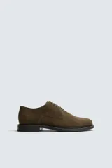 Zapato tipo derby con cordones, confeccionado en piel con acabado de serraje. Presenta horma redonda y suela a contraste.