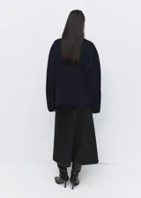Abrigo corto de paño en color azul marino, con cuello alto, cierre frontal con botones ocultos y diseño de corte holgado.