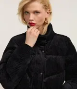 Campera puffer de mujer con diseño acolchado y textura acanalada tipo cotelé. Presenta cuello alto, cierre frontal con botones a presión y puños elásticos.