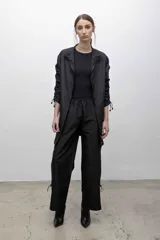 Vestido negro de microfibra con corte recto, cuello alto, cierre frontal y mangas largas con sistema de frunce ajustable.