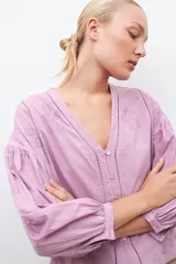 Blusa blanca de manga larga con escote en V y bordados en el frente.