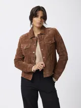 Campera de cuero gamuzado en color marrón, con diseño tipo trucker, cuello camisero, cierre frontal con botones metálicos y bolsillos con solapa en el pecho.