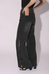 Pantalón de jean gris oscuro de corte acampanado, con tachas metálicas plateadas en los laterales.