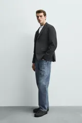 Blazer regular fit de bouclé con diseño pata de gallo en tonos oscuros, solapas de muesca, cierre de un botón y bolsillos con solapa en la cadera.