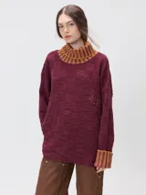 Pullover de punto jacquard con diseño de cuadros en relieve, cuello alto y mangas largas. Presenta detalles de pespuntes en color rojo en el cuello y los puños, aberturas laterales y logo bordado en el pecho.